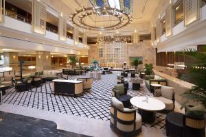 eine Hotellobby mit Tischen, Stühlen und einem Kronleuchter in der Unterkunft Lotte Hotel Saigon in Ho-Chi-Minh-Stadt