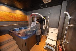 a man in a bath tub in a room at サポートイン南知多 in Utsumi