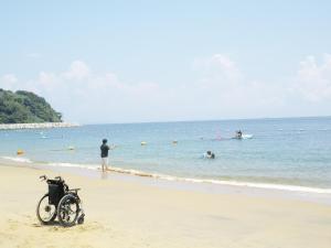 a motorcycle parked on the beach with people in the water at サポートイン南知多 in Utsumi