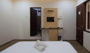 a bedroom with a bed and a desk with a television at SIMPANG 7 RESIDENCE in Kudus