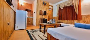 a bedroom with a bed and a table and a refrigerator at IVA Manali- A Luxury Mountain View Cottages in Manāli