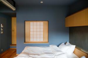 - une chambre bleue avec un lit et une fenêtre dans l'établissement Temari Inn Madoromi, à Kurashiki