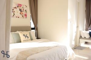 a bedroom with a bed with white sheets and a window at Homesuite' Home at The Shore in Kota Kinabalu