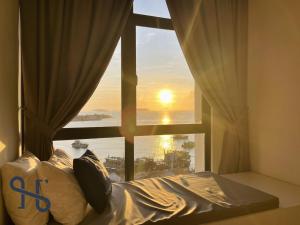 a bedroom with a window with a view of the sunset at Homesuite' Home at The Shore in Kota Kinabalu