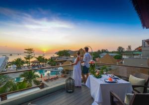 Una pareja de pie en un balcón con vistas a la puesta de sol en Ananya Lipe Resort, en Ko Lipe