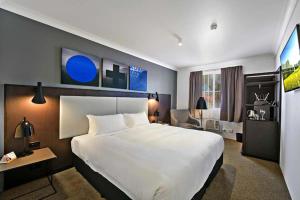a hotel room with a large bed and a television at CKS Sydney Airport Hotel in Sydney