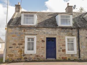 une ancienne maison en pierre avec une porte bleue dans l'établissement Alt na Voir, à Tomintoul
