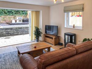 a living room with a leather couch and a television at Clock Tower Cottage in Whitchurch