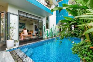 a swimming pool in front of a house with plants at An Bang MQ Villa in Hoi An
