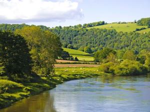 um rio flui através de um vale com árvores e campos em Clock Tower Cottage em Whitchurch