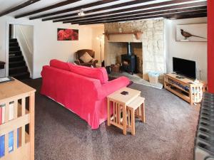 Grooms Bothy في بيلينجهام: غرفة معيشة مع أريكة حمراء ومدفأة