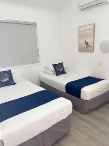 Cette chambre blanche comprend 2 lits. dans l'établissement Marlin Villa - Hervey Bay, à Urangan