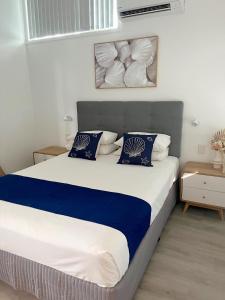 a bedroom with a large bed with blue and white pillows at Marlin Villa - Hervey Bay in Urangan