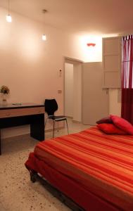 a bedroom with a desk and a bed with a red blanket at Casina delle Palme in Trapani