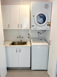 a kitchen with a sink and a washing machine at Marlin Villa - Hervey Bay in Urangan