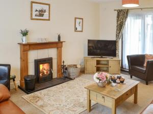 a living room with a fireplace and a tv at Thistle Dee in Wooler