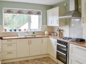 a kitchen with white cabinets and a sink and a window at Thistle Dee in Wooler