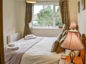 a bed in a bedroom with a window and two lamps at Thistle Dee in Wooler