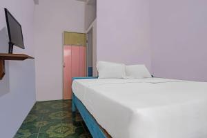 een wit bed in een kamer met een rode deur bij SPOT ON 92421 City Kost Syariah in Pangkalpinang