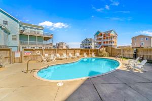 a swimming pool with patio furniture and a building at Hatteras Memories in Hatteras