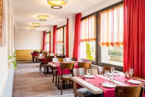 a restaurant with tables and chairs and red curtains at Pension Haus Anny in Deudesfeld