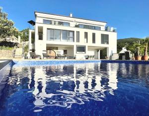 a house with a swimming pool in front of a house at Villa White Pearl Diamond Haus B, Opatija mit Meerblick & Pool in Opatija