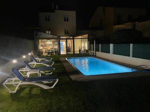 a pool with lounge chairs next to a house at night at Pension San Anton in Melide