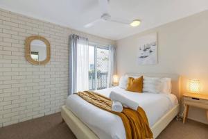 a white bedroom with a large bed and a window at Beach Haven at Alex Heads in Alexandra Headland