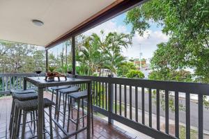 een balkon met een tafel en stoelen en uitzicht op een straat bij Beach Haven at Alex Heads in Alexandra Headland