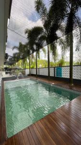 a swimming pool with palm trees and a wooden deck at Saka Hotel Medan in Sunggal