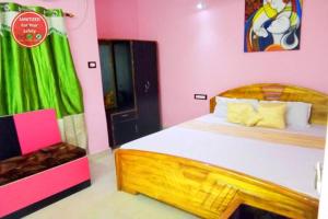 - une chambre rose avec un lit en bois dans l'établissement Goroomgo Swapanodeep Digha, à Digha