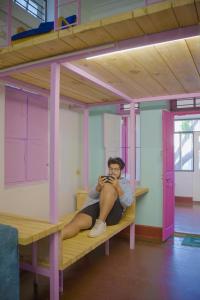 mężczyzna siedzący na łóżku piętrowym w pokoju w obiekcie Rahee Bi Roambay - Backpacker Hostel w mieście Mysuru