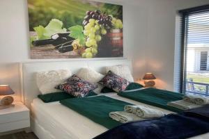 uma cama com dois lençóis verdes e uma imagem de uvas em Holiday villa for 6 p with garden on the water in green surroundings near Harderwijk em Zeewolde