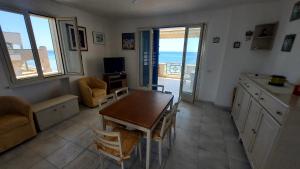 una cucina con tavolo e una sala da pranzo con vista sull'oceano di 058 Spiaggia di SalentoInVacanza.Com a Torre Pali