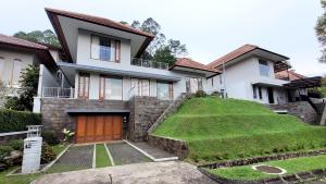 una casa con una colina de hierba delante de ella en Japanese Style Villa at Dago Bandung 4BR Soo Maison, en Bandung