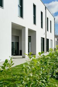 維也納新城的住宿－Lamede，白色的房子,有黑色的窗户和绿色的植被