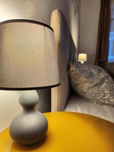 a white lamp sitting on a table next to a bed at Armina's Residence in Dumbrăviţa