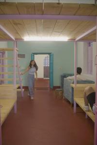 kobieta przechodząca przez pokój z łóżkiem piętrowym w obiekcie Rahee Bi Roambay - Backpacker Hostel w mieście Mysuru