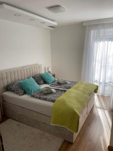 een slaapkamer met een bed met groene en blauwe kussens bij Sunshine Resort Brown apartman in Zamárdi