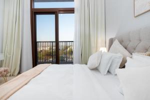 a bedroom with a large white bed and a window at Town Square in Dubai