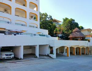 a white building with a car parked in front of it at Twin Towers Tres Mares in Acapulco