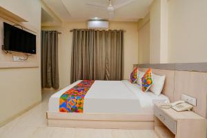 a bedroom with a bed with a phone and a television at FabHotel Bhiwandi Palace in Mumbai