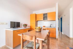 cocina con armarios naranjas y mesa de madera en Lido Marini Apartments - Happy Rentals, en Salve
