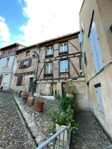 an old building with potted plants in front of it at Le Logis Plantagenêt in Bergerac