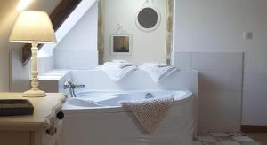 a white bathroom with a tub and a lamp at Manoir de Pierreville in Audouville-la-Hubert