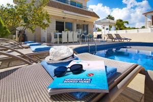 een boek en zonnebril op een tafel naast een zwembad bij Villa Sonja in Protaras