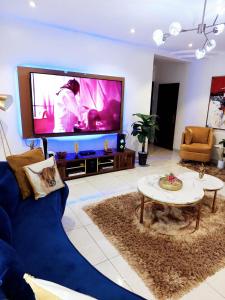 - un salon avec une grande télévision et un canapé bleu dans l'établissement HOMEDALES Freedom Way LEKKI Phase1 LAGOS, à Lekki