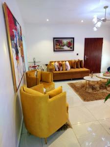 a living room with yellow chairs and a couch at HOMEDALES Freedom Way LEKKI Phase1 LAGOS in Lekki