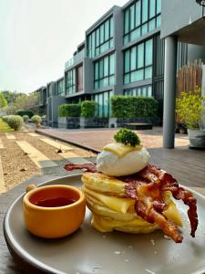 a plate with a breakfast sandwich with bacon and eggs at Zensala Riverpark Resort-SHA Extra Plus in Chiang Mai