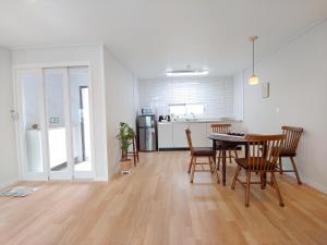 a living room with a table and chairs and a kitchen at Viravi Stay in Jeju